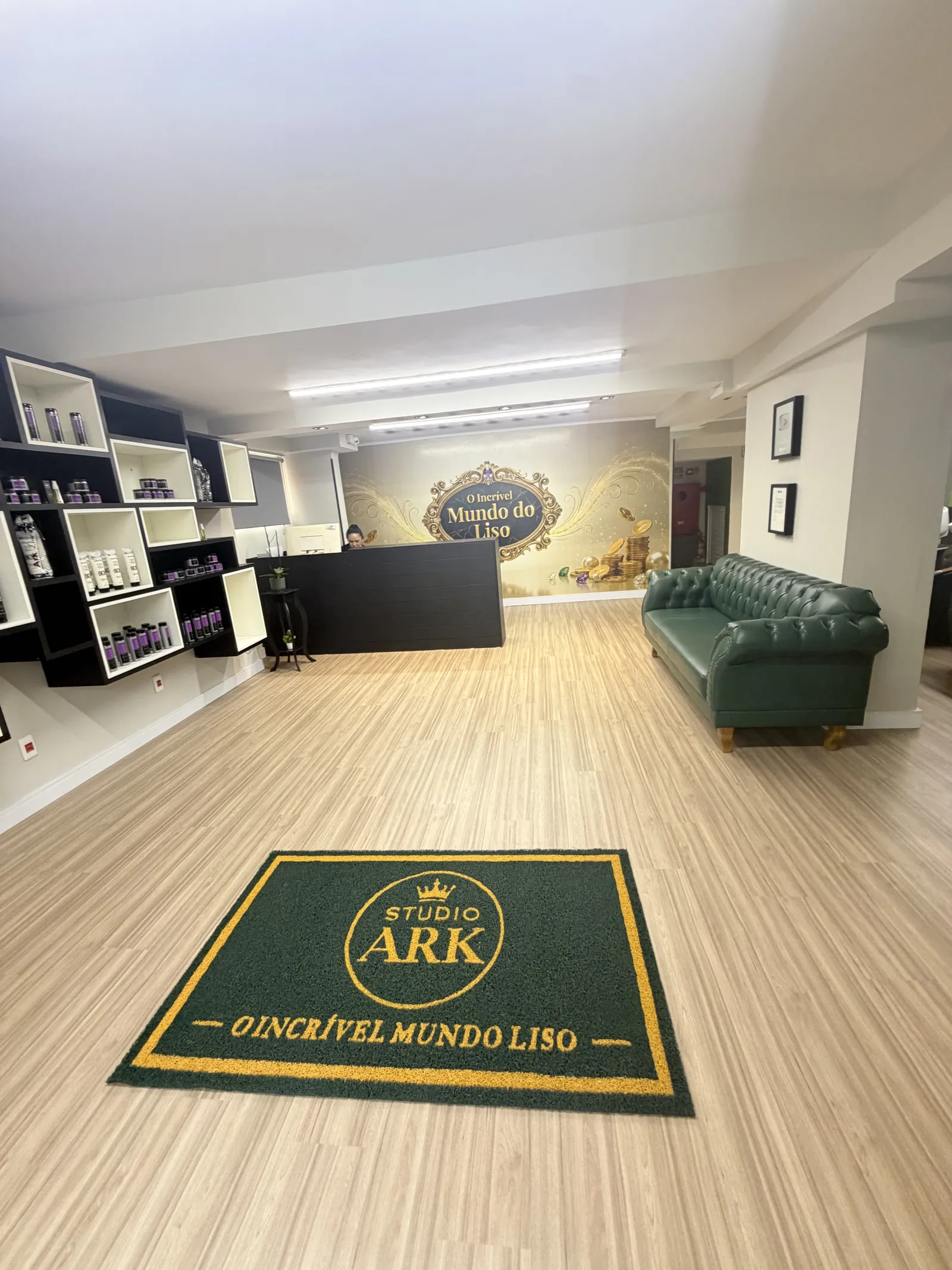 Balcão da recepção do Studio Ark, painel O Incrível Mundo do Liso e tapete verde com a marca do salão.